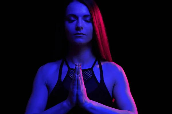 Junge fitte Frau beim Meditieren. Neonlicht. Moderne Science-Fiction-Darstellung von Yoga. Kopierraum. — Stockfoto