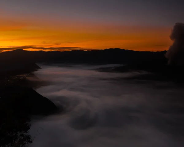 The fog creeps over the water under an orange sky (Bohorok, Indonesia) — Stock Photo, Image