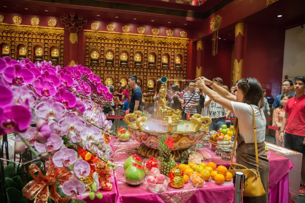 Cuenco con Buda en una mesa con frutas y orquídeas en el Templo de la Reliquia del Diente Sagrado, Singapur Imágenes De Stock Sin Royalties Gratis