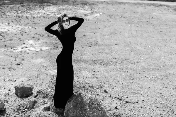 Hübsche Frau im langen schwarzen Kleid, die draußen spazieren geht — Stockfoto