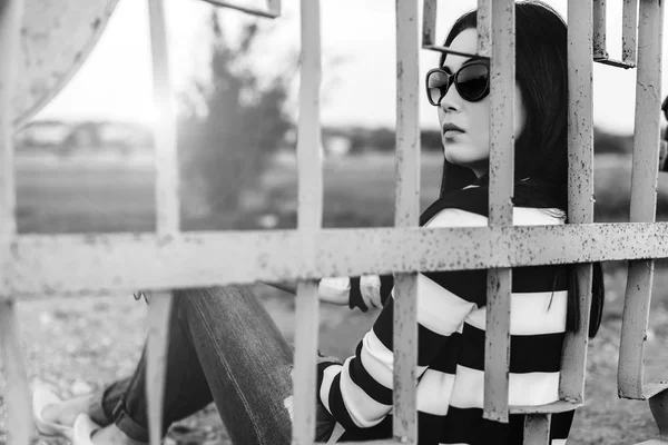 Mujer joven sentada detrás de la cerca — Foto de Stock