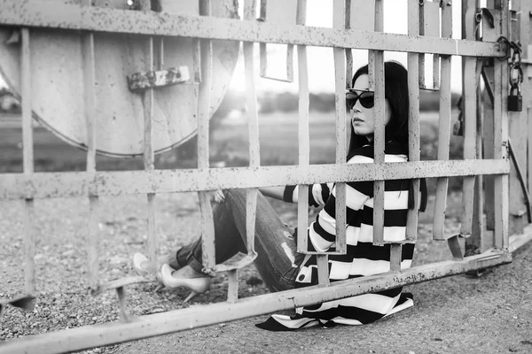 Jeune femme assise derrière une clôture — Photo
