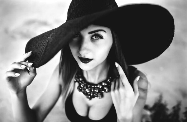 Young pretty woman on the beach in black hat, black and white photo