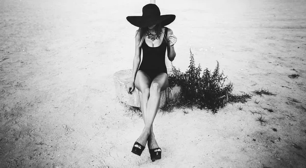 Giovane bella donna sulla spiaggia in cappello nero — Foto Stock