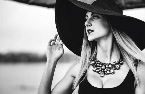 Young pretty woman on the beach in black hat — Stock Photo, Image