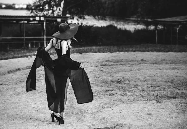 Jovem mulher bonita na praia em chapéu preto — Fotografia de Stock