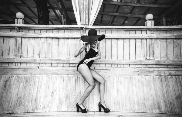 Hezká mladá dívka stojící dřevěné zdi v černé plavky — Stock fotografie