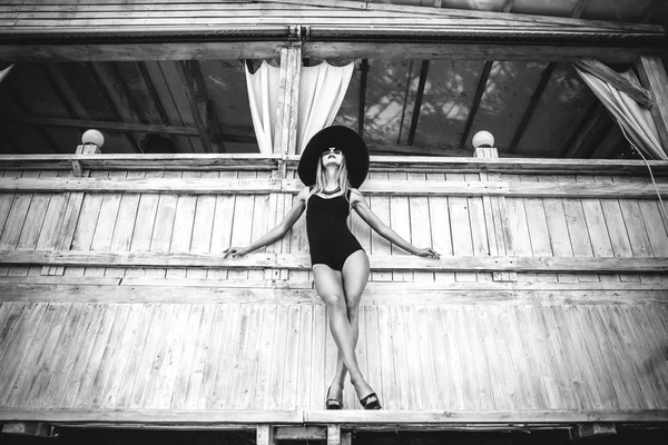 Genç ve güzel kız ahşap duvar siyah mayo ayakta — Stok fotoğraf