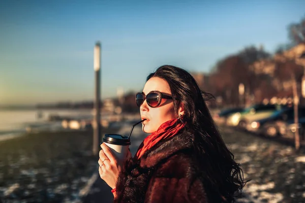 Brunett tjej gå utomhus i parken med kopp kaffe — Stockfoto