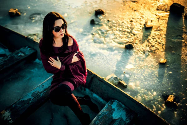 Brunette girl sitting outdoor in the old boat — Stock Photo, Image