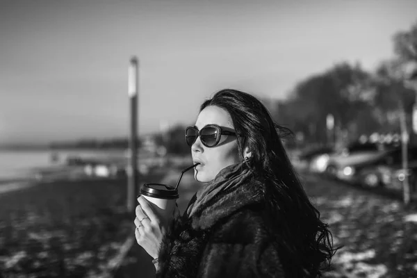 Brunett tjej gå utomhus i parken med kopp kaffe — Stockfoto