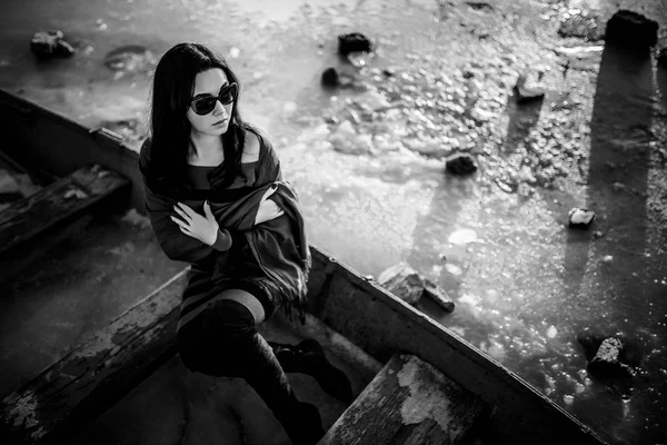 Брюнетка девушка сидит на открытом воздухе в старой лодке — стоковое фото