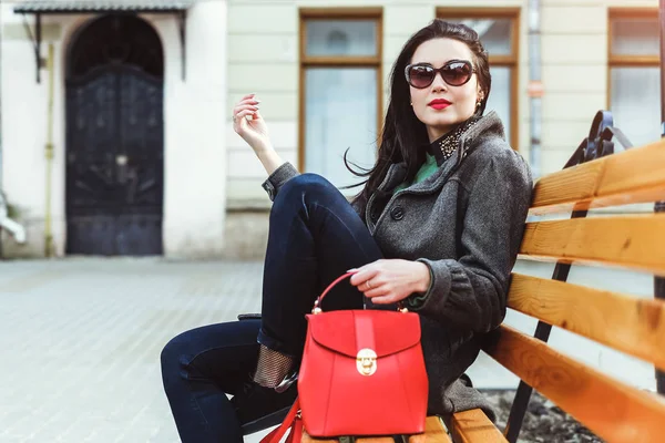 Женщина сидит с красной сумкой — стоковое фото