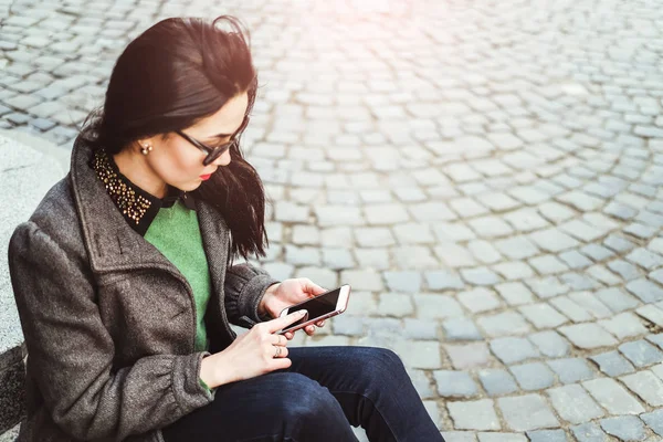 Menina morena sentada com celular — Fotografia de Stock