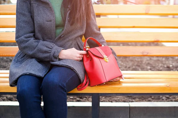 Donna seduta sulla panchina con borsa rossa in mano — Foto Stock