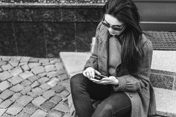 Brunette meisje zittend op straat — Stockfoto