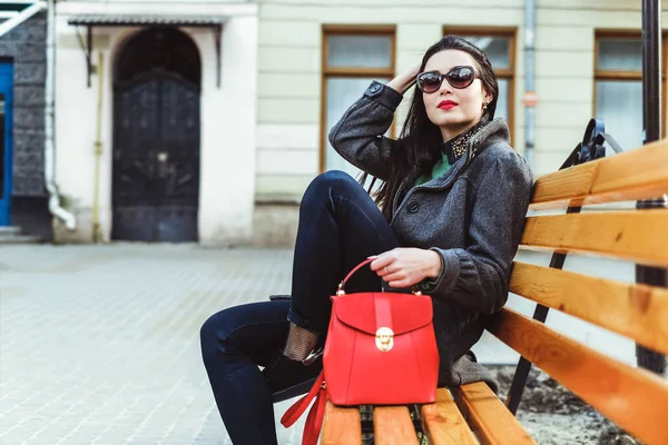 Mulher sentada no banco com saco vermelho — Fotografia de Stock