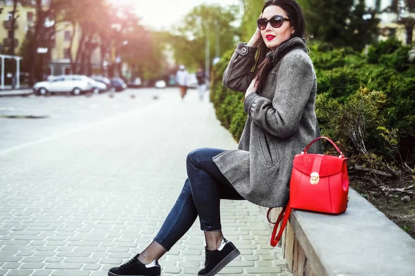 Брюнетка сидит на улице с красным рюкзаком — стоковое фото
