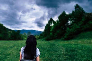 Kadın bulutlu gökyüzü ile dağlarda