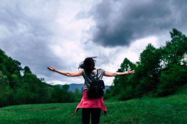 Kadın bulutlu gökyüzü ile dağlarda