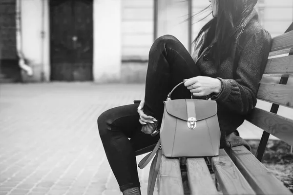 Vrouw zitten op bankje met tas — Stockfoto