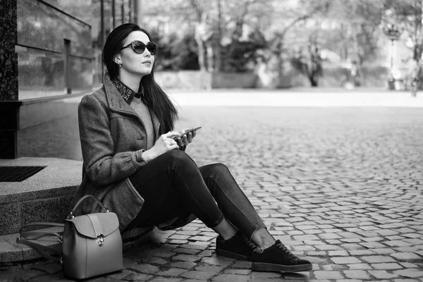 Дівчина сидить на вулиці з мобільним телефоном — стокове фото
