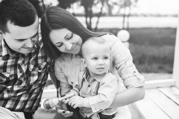 Gelukkige jonge ouders met zoontje spelen buiten in het park — Stockfoto