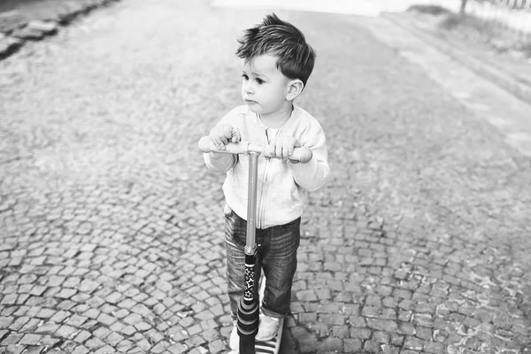 Mooie kleine jongen rijden scooter buiten — Stockfoto