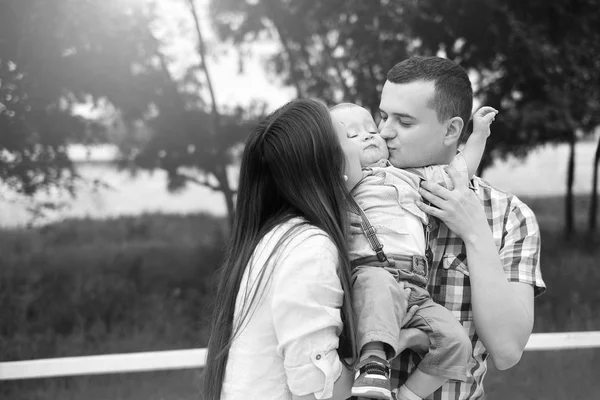 Padres jóvenes felices con su pequeño hijo jugando al aire libre en el parque —  Fotos de Stock