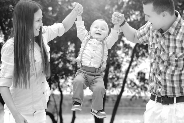 Счастливые молодые родители с маленьким сыном играют на свежем воздухе в парке — стоковое фото