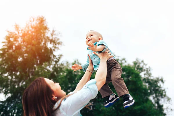 Feliz jovem mãe brincando com seu pequeno filho ao ar livre — Fotografia de Stock