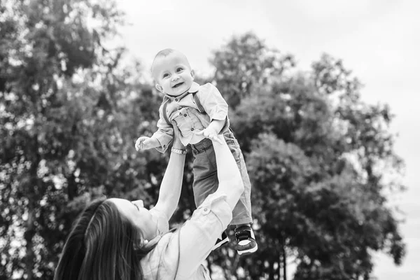 Щаслива молода мати грає зі своїм маленьким сином на відкритому повітрі — стокове фото