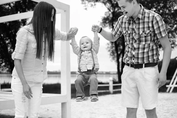 Padres jóvenes felices con su pequeño hijo jugando al aire libre en el parque —  Fotos de Stock