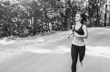 Genç bayan parkta koşuyor.