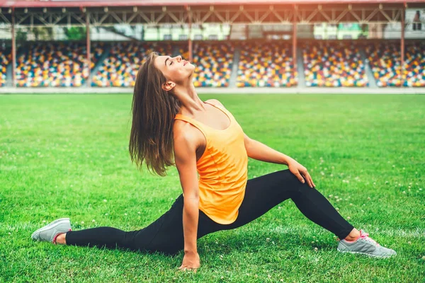 Woman stretching on football field — Stock Photo, Image