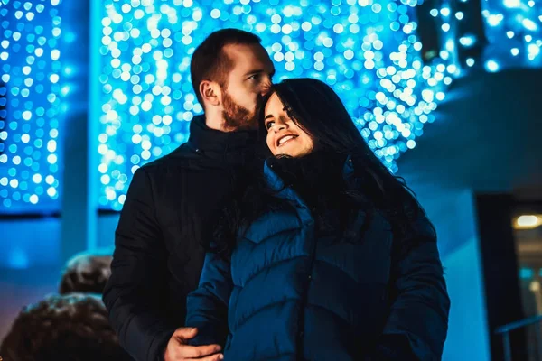 Pareja feliz enamorada de las luces de Navidad detrás — Foto de Stock