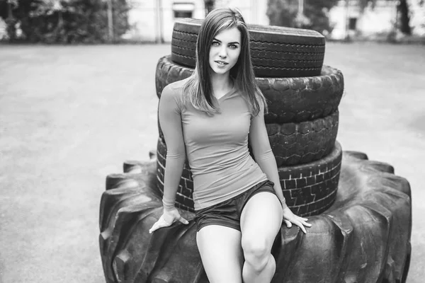 Sportovní hezká dívka v blízkosti obrovské pneumatiky venkovní — Stock fotografie