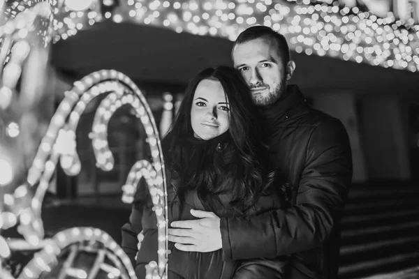 Casal feliz no amor com luzes de Natal atrás — Fotografia de Stock