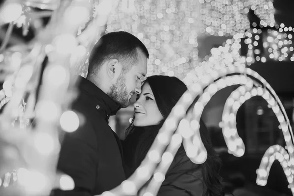 Lyckliga par i kärlek med julbelysning bakom — Stockfoto