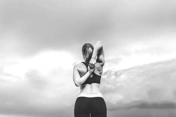 Симпатичная спортивная девушка, демонстрирующая растяжки на открытом воздухе, черная и — стоковое фото