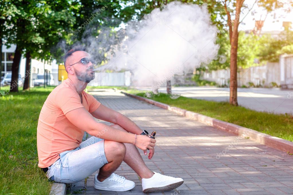 man with beard and electronic cigarette outdoor in summer