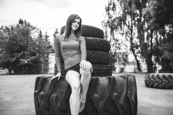 Docela sportovní dívka cvičení venku s velkými pneumatiky — Stock fotografie