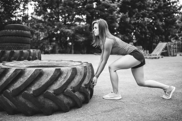 夏の公園で大きなタイヤで屋外作業をスポーティーな少女 — ストック写真