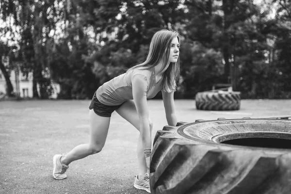 夏の公園で大きなタイヤで屋外作業をスポーティーな少女 — ストック写真