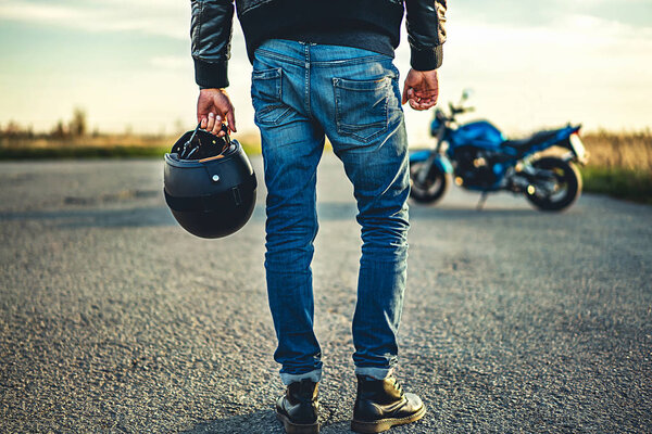 Colorful shot of male biker with sport motorcycle outdoor on road at daytime
