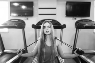 Güzel genç bir bayanla uzun saç eğitim salonunda. Genç kadın fitness ekipmanları ile egzersiz