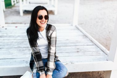 Ahşap katta oturan ve parkta açık rahatlatıcı genç çekici esmer kadın