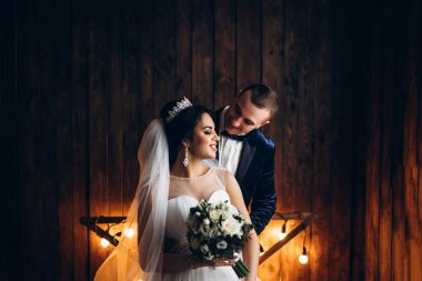 Genç Düğün çifti ile ışık ahşap duvar önünde poz