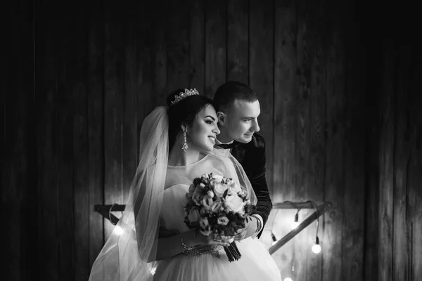 Junges Hochzeitspaar Posiert Vor Holzwand Mit Lichtern — Stockfoto