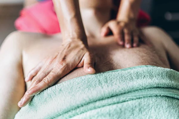 En kvinnlig sjukgymnast som gör massage för en man i medicinska o — Stockfoto